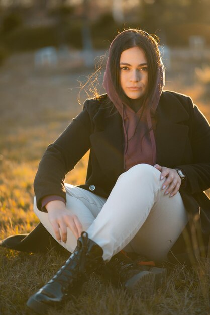 Photo a woman in a hoodie looking at the camera during sunset