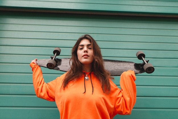 Woman in hoodie stands with a longboard in her hands