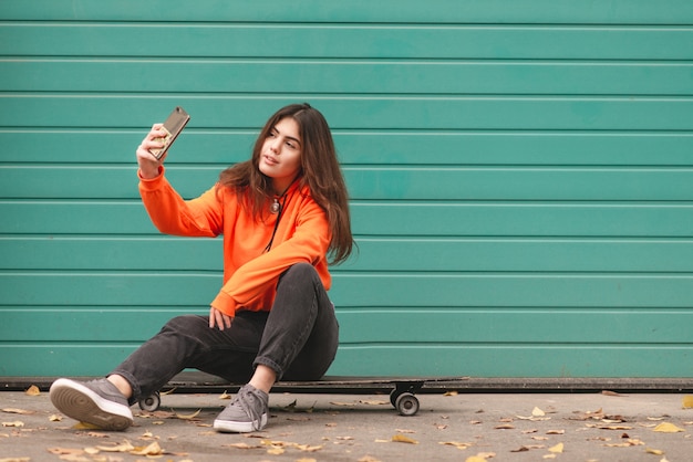 La donna in felpa con cappuccio sta con un longboard