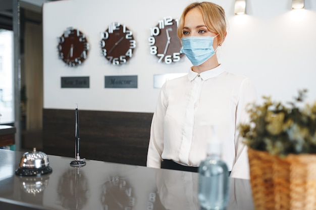 Портье отеля женщина в медицинской маске для защиты от коронавируса