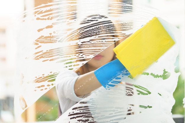 Woman housekeeper cleaning the mirror with yellow sponge