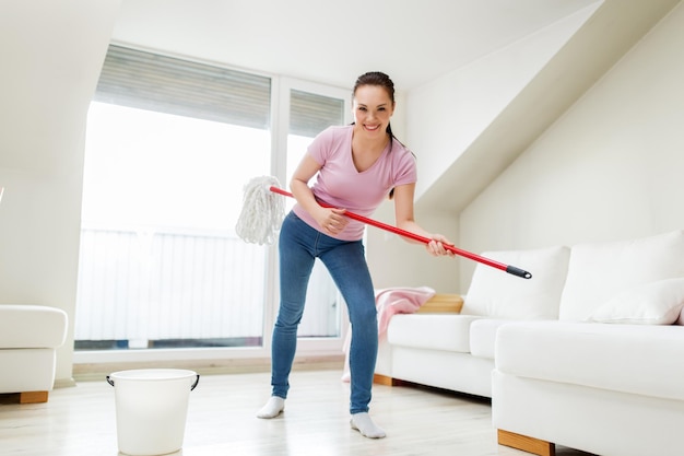 woman or housewife with mop cleaning floor at home