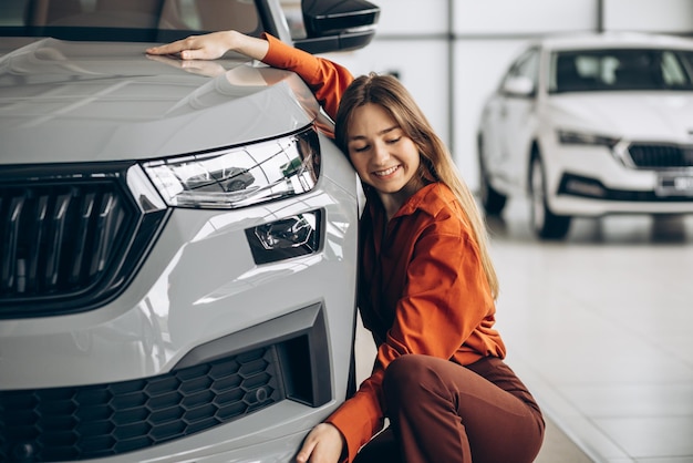 Photo woman hugging a car in a car showroom