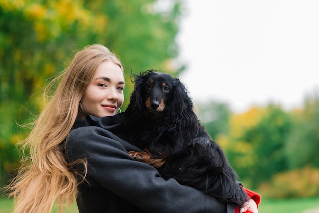 Woman hugging dog in the summer park.