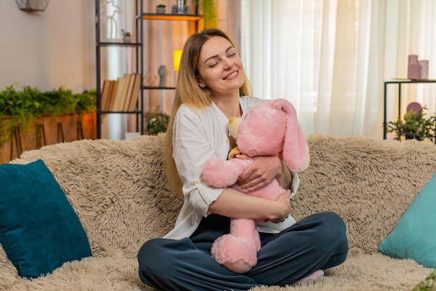家で毛皮のおもちゃを抱きしめている女性 慰めと落ち着きで笑顔を浮かべ 安全感を感じ 感情的に根付いています