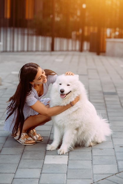 Woman hugs a big dog at sunset