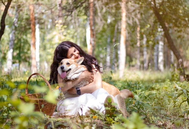 Woman hugs a corgi dog in the forest