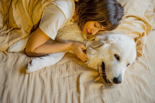 Woman hugs with her cute dog in bed