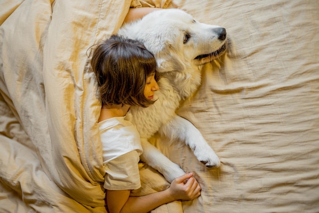 Woman hugs with her cute dog in bed