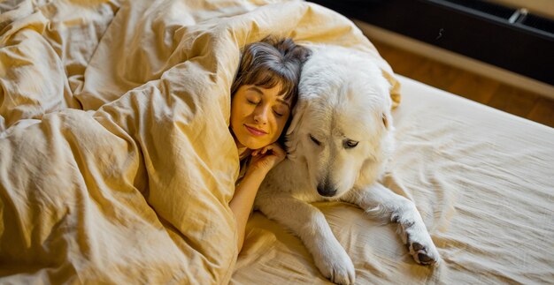 Woman hugs with her cute dog in bed