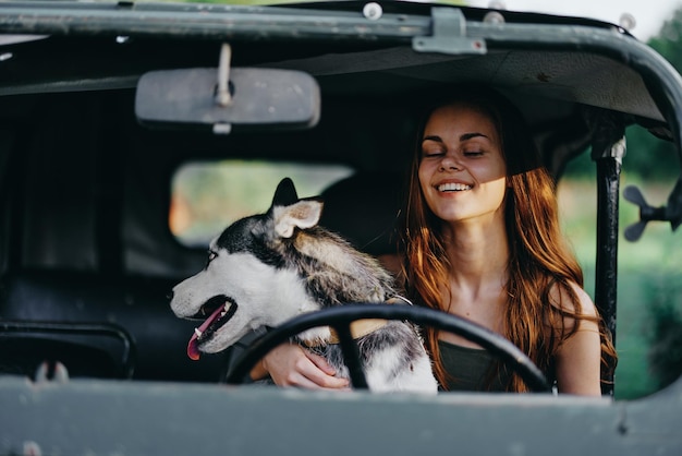 車の中で幸せに旅行する女性とハスキー犬は、歯が落ちて笑顔で歩き、犬の友人と抱擁して踊るペット旅行と散歩します