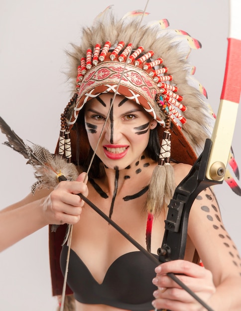 The woman in the image of indigenous peoples of America with a bow and arrow poses on a white background