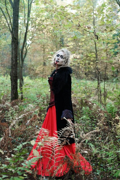 A woman in the image of a vampire or a witch with white makeup and in a medieval dress