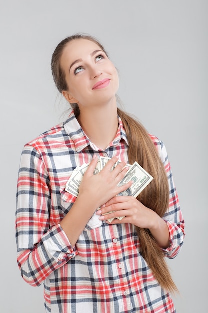 Фото Женщина в клетчатой рубашке держит долларовые купюры