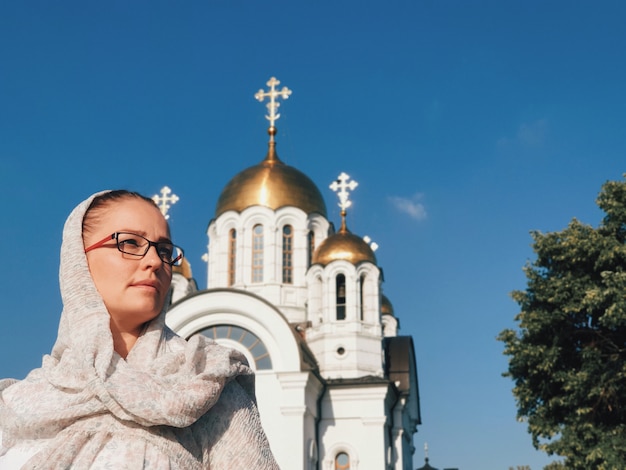 Фото Женщина в платке стоит на православной церкви