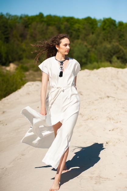 Фото Женщина в белом платье идет по песку