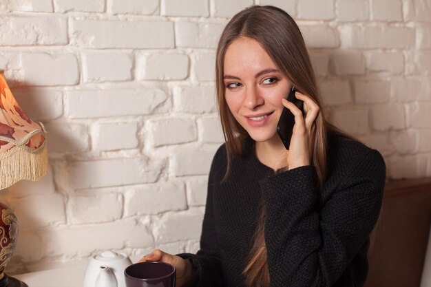 Фото Женщина в кафе пьет чай и пользуется своим смартфоном