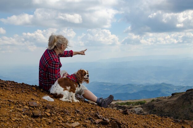 写真 犬と一緒にいる女性が ⁇ 山の頂上から美しい山の風景を示しています ⁇