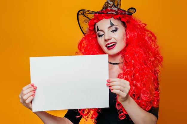 Фото Женщина в костюме хеллоуина, держа белый лист бумаги.