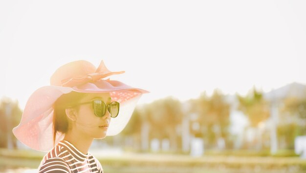 写真 帽子とサングラスをかぶった女性が空に向かって