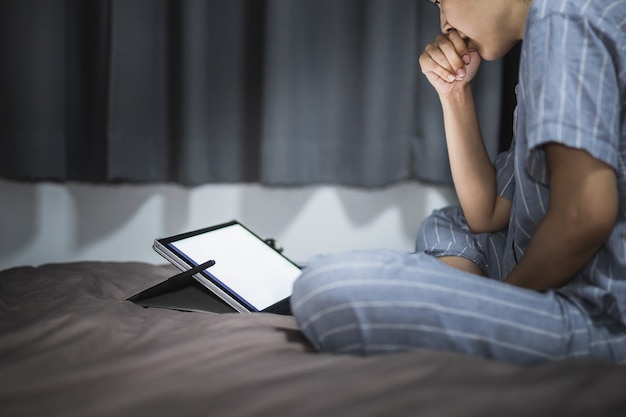 Фото Женщина в пижаме, используя ноутбук в постели ночью.