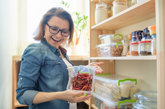 写真 赤苦い唐辛子とコンテナーを保持しているパントリーの女性