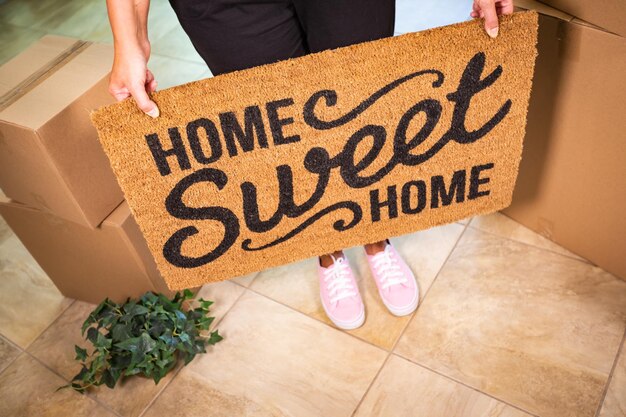 写真 ピンクの靴を履いた女性が家を抱いている 甘い家 ウェルカムマットボックスとプラント