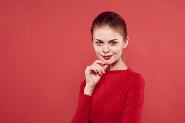 Фото Женщина в красном свитере макияж привлекательный взгляд красный фон