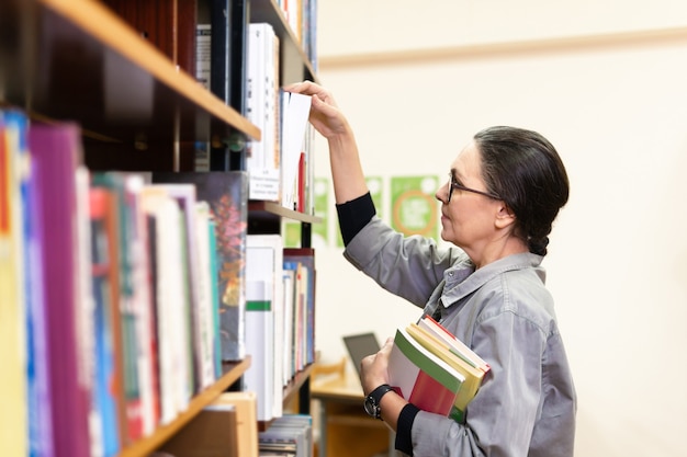 写真 本棚の前の図書館の女性。教育の概念