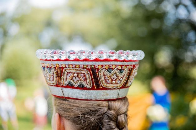 写真 伝統的なラトビアの衣装を着た女性と国家の王冠のクローズアップ