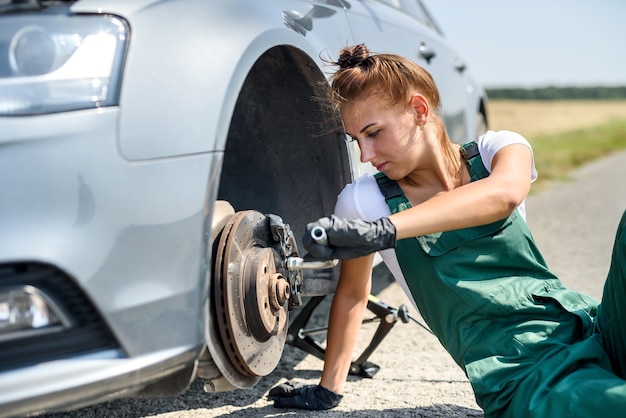 Фото Женщина в униформе, работающая для обслуживания тормозов автомобиля. ремонт машин. безопасная работа