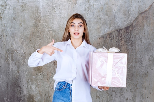 핑크 선물 상자를 들고 흰 셔츠에 여자는 흰색 리본으로 포장.