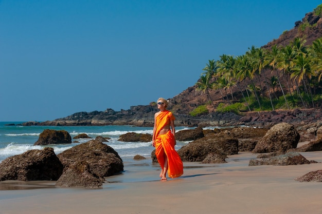 Woman in indian clothes on the beach on a background of palm trees