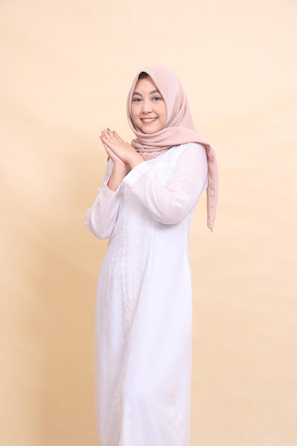 woman indonesia wearing a beautiful Muslim dress smiling cheerfully poses holding hands together iso