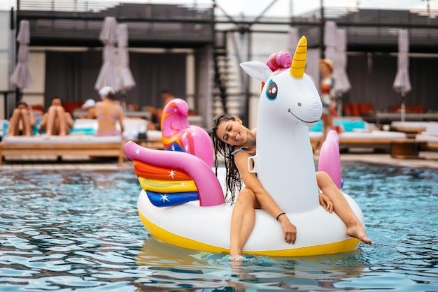 Woman on inflatable unicorn toy mattress float in pool