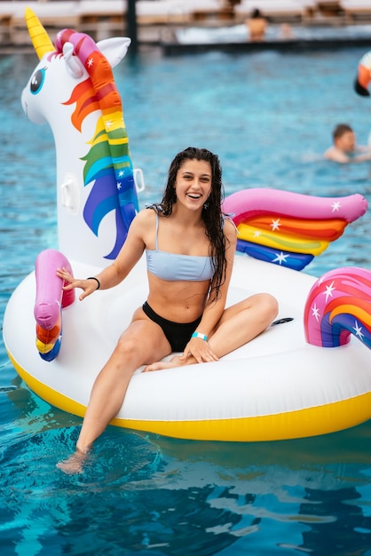 Woman on inflatable unicorn toy mattress float in pool