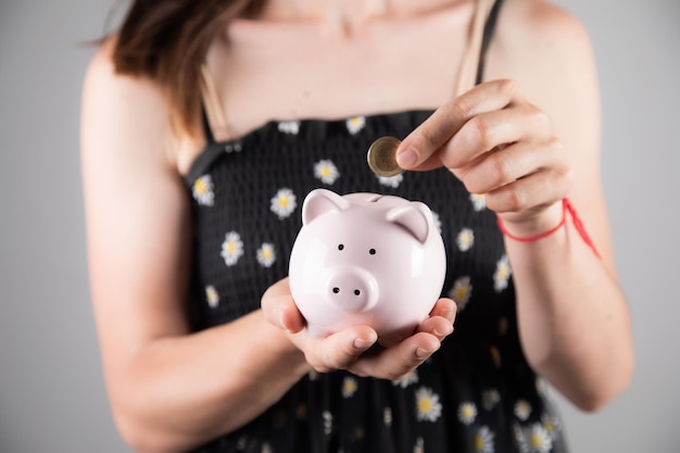 Woman inserting a coin into a piggy bank