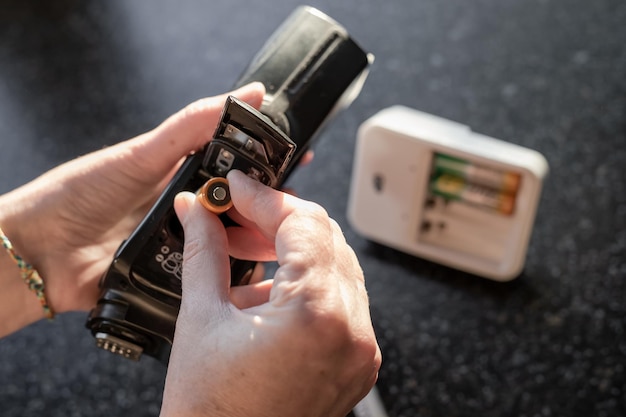 Photo a woman inserts batteries into a camera flash to take pictures