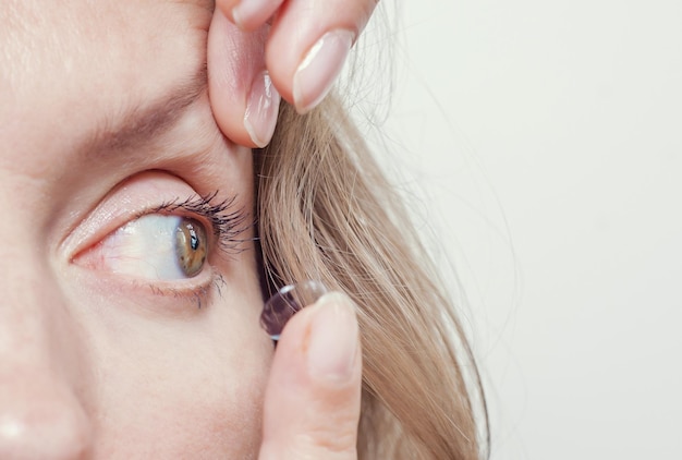 Woman inserts a contact lens into the eye