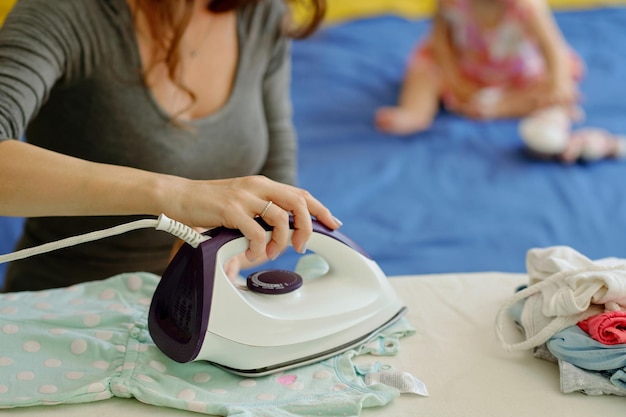 Woman Ironing Tidy Baby Clothes