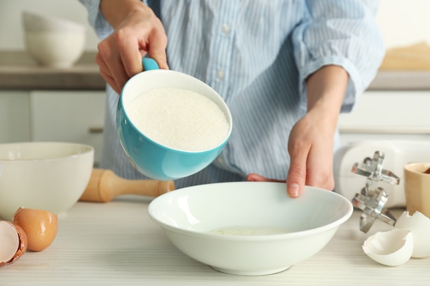 Photo woman is adding sugar to the egg mixture