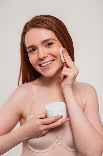 A woman is applying a face cream to her face.