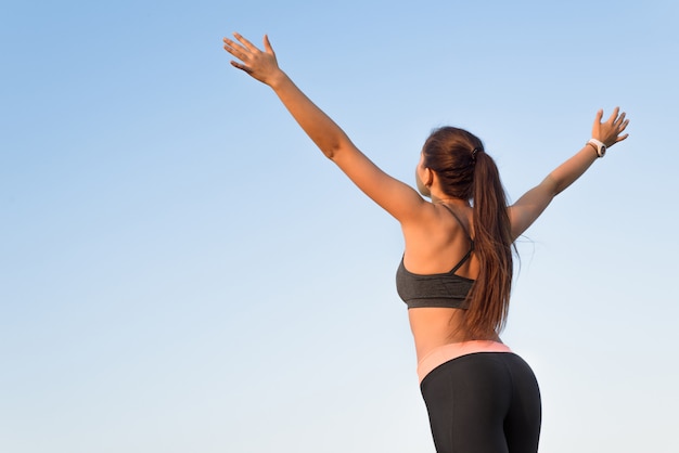 Woman is back raising arms to the sky.