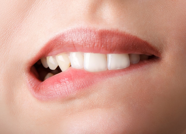 Woman is biting her red lips by teeth