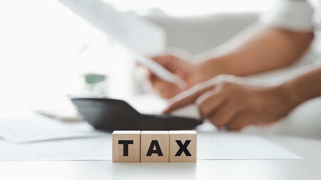 Woman is calculating annual tax, monthly expenses with\
calculator and filling form of individual income tax return. season\
to pay tax and budget planning concept.