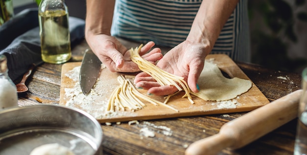 La donna sta tenendo con attenzione le tagliatelle fatte in casa fresche crude nelle sue mani