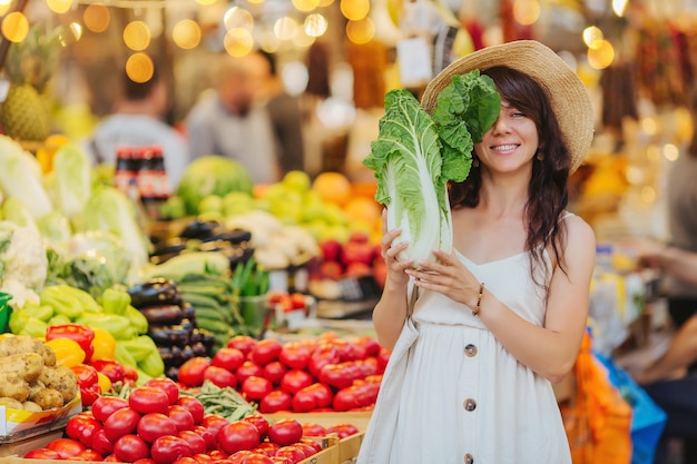 여자는 식품 시장에서 과일과 야채를 선택합니다. 쇼핑을 위한 재사용 가능한 에코백. 제로 폐기물 개념입니다.