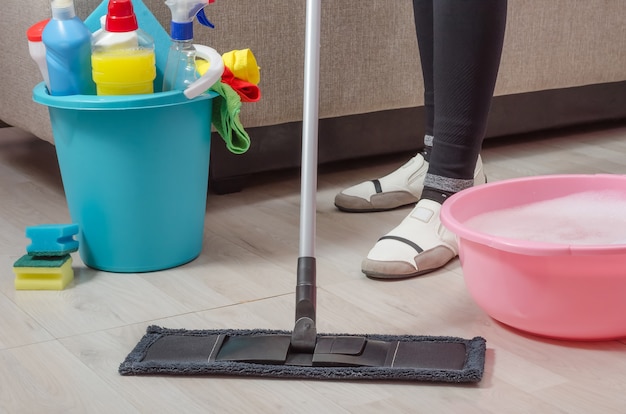 Una donna sta pulendo la casa, l'appartamento, lava il pavimento in parquet con uno straccio e detersivo.