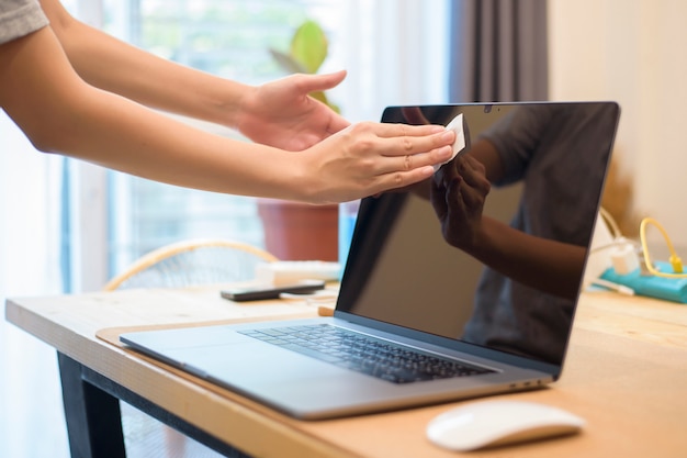 Woman is cleaning laptop by alcohol spray