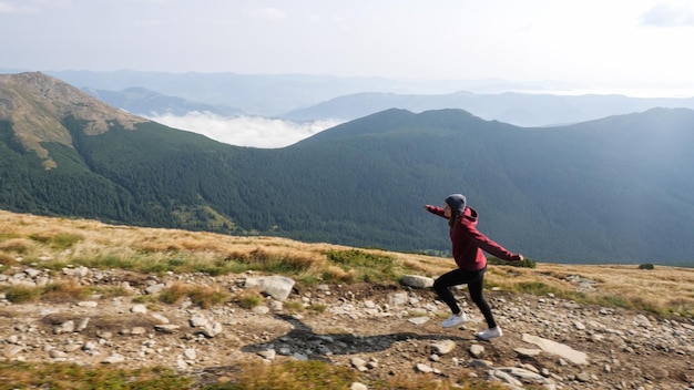 女性は山の石の谷を通過する山の尾根を登っています